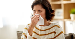 Woman blowing nose into a tissue