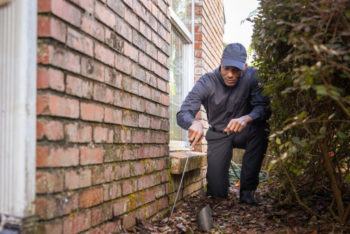 Pest control service Technician inspecting the outside of a home