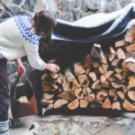 Person collecting logs of wood from a wood pile - keep pests away from your home with Arrow Exterminating Company in NY