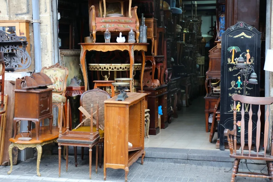 A storefront packed with a variety of used wooden furniture, antique chairs, and vintage home decor.
