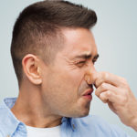 Man holding nose due to bad smell