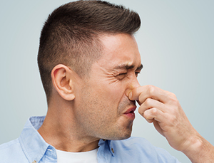 Man holding nose due to bad smell