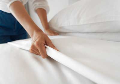 a person strips the bedding off before getting bed bug treatment