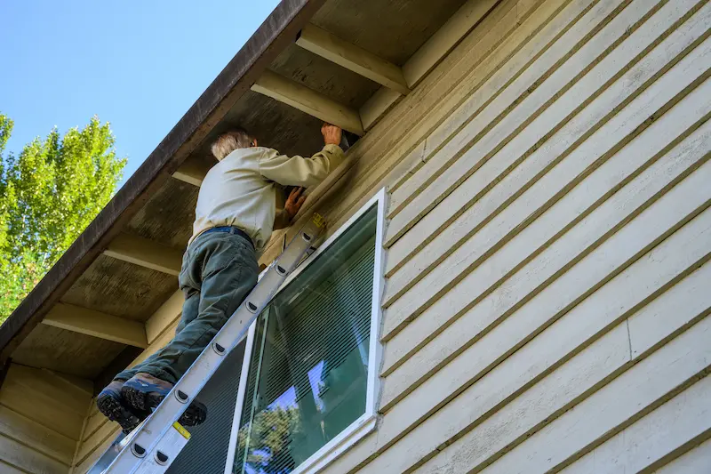 Professional installing a vent cover in the eves of a two story home.